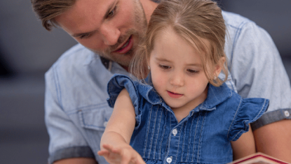 father and daughter reading a book together